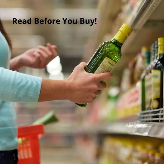 A person in a supermarket reading the label on a bottle of olive oil taken from a shelf. The text overlay on the image says, "Read Before You Buy!